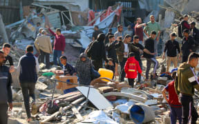 Palestinians sift through destroyed shelters at a UNRWA school housing displaced people, following an Israeli strike in the Bureij refugee camp in the centre of the Gaza Strip, on 7 May , 2025.