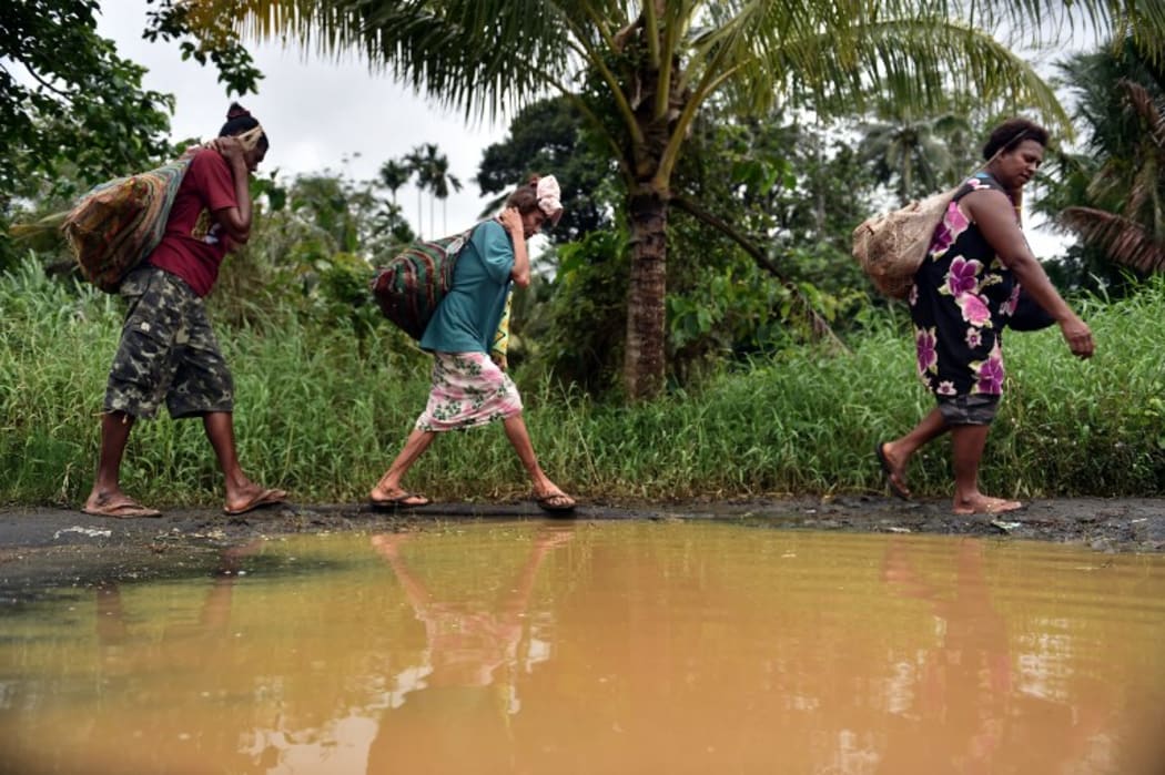 Women carry wood in the town of Kerema, Papua New Guinea