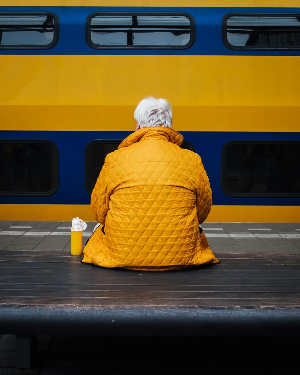 woman in yellow jacket in front of yellow bus
