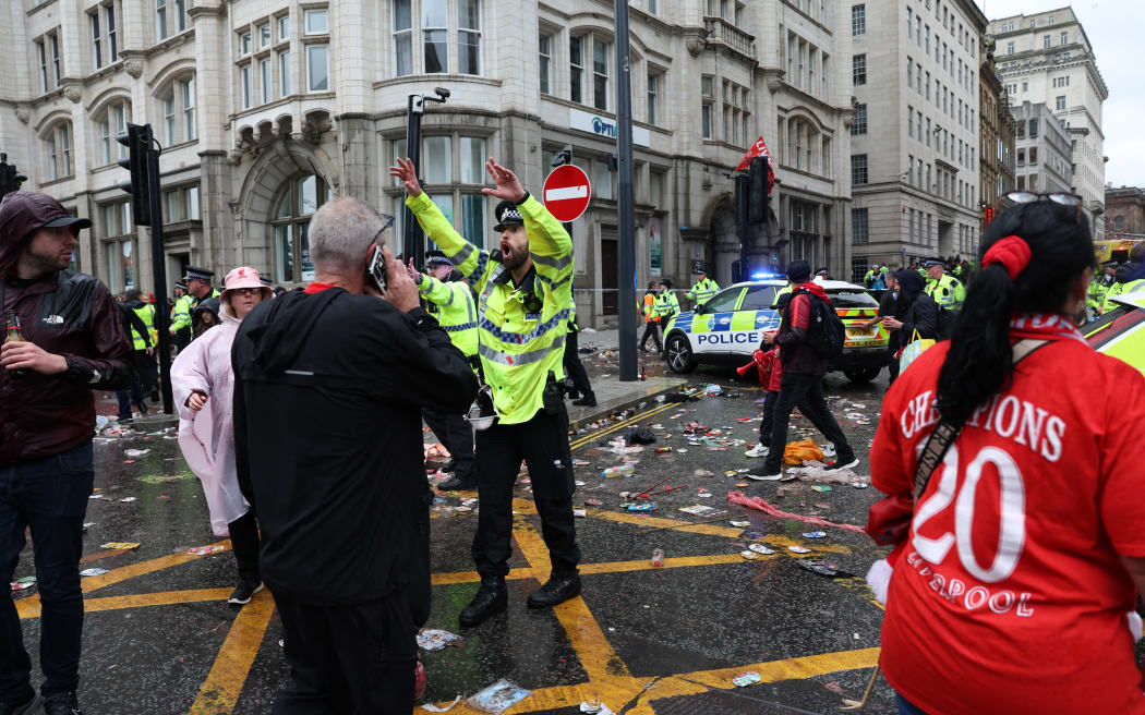 A Police officer shouts at Liverpool fans at the scene of an incident, on the sidelines of an open-top bus victory parade for Liverpool's Premier League title win.