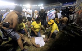 Rescuers attend an injured man lying on the pitch following a stampede during a football match between Alianza and FAS at Cuscatlán stadium in San Salvador on 20 May, 2023, which killed at least nine people.