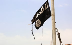 A member of the Syrian Democratic Forces (SDF) removes an Islamic State group flag in the town of Tabqa,  west of Raqa city, as they advance in their battle for the group's de facto capital.