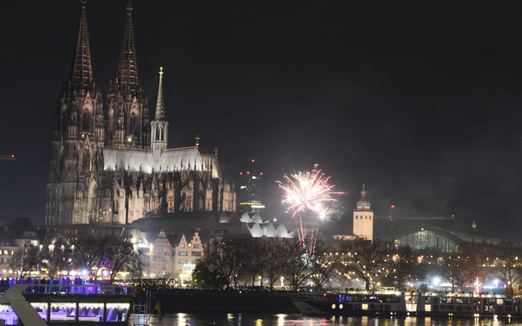 People celebrate with fireworks along the Rhine River as the Dom Cathedral is seen in the background during the celebration for the upcoming New Year's Eve in Cologne, Germany, on December 31, 2024. (Photo by Ying Tang/NurPhoto) (Photo by Ying Tang / NurPhoto / NurPhoto via AFP)