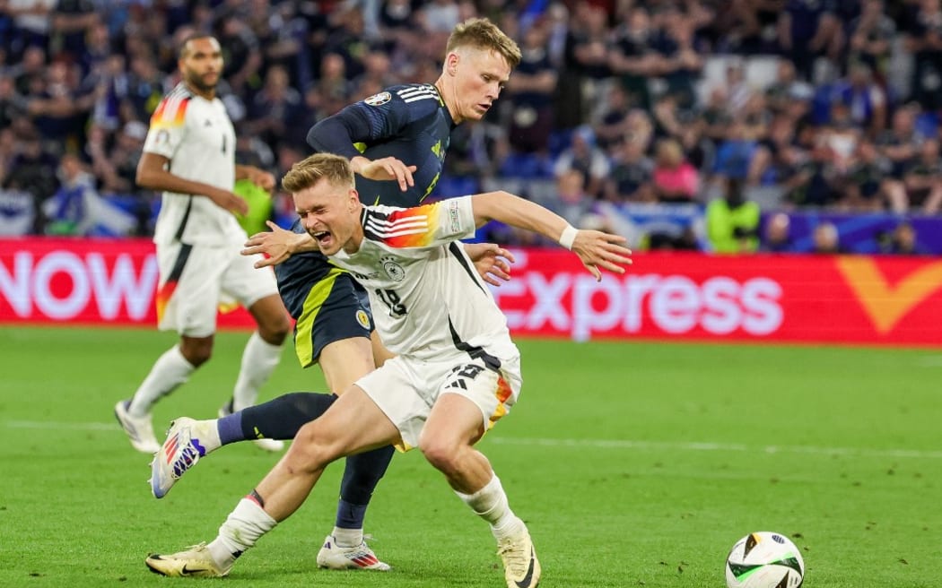 14 June 2024, Bavaria, Munich: Soccer, UEFA Euro 2024, European Championship, Germany - Scotland, Preliminary round, Group A, Matchday 1, Football Arena Munich. Germany's Maximilian Mittelstädt (front) and Scotland's Scott McTominay in a duel. Photo: Christian Charisius/dpa (Photo by CHRISTIAN CHARISIUS / DPA / dpa Picture-Alliance via AFP)
