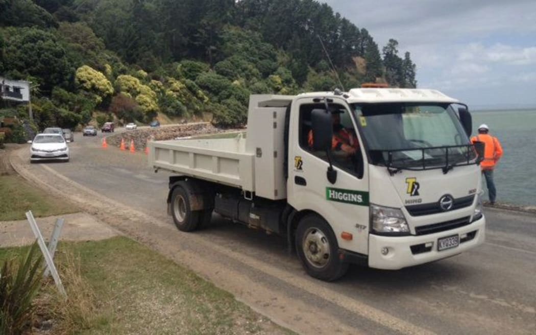 A truck leads a slow convoy through a repaired lane on the Thames Coast Road.