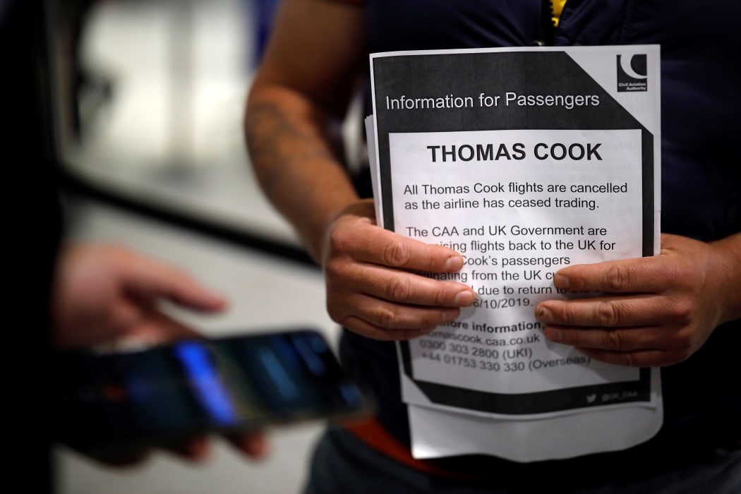 An affected passenger holds an information leaflet after arriving at the closed Thomas Cook check-in desk at the South Terminal of London Gatwick Airport in Crawley, south of London on September 23, 2019.