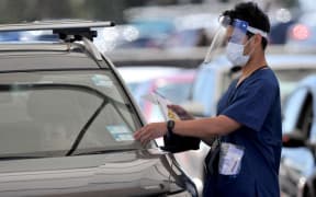 A health official collects a COVID-19 swab test at a drive-through testing site on Bondi beach in Sydney on December 15, 2021, as rapidly-growing Omicron and Delta clusters brought more than 2,700 new cases nationally.
