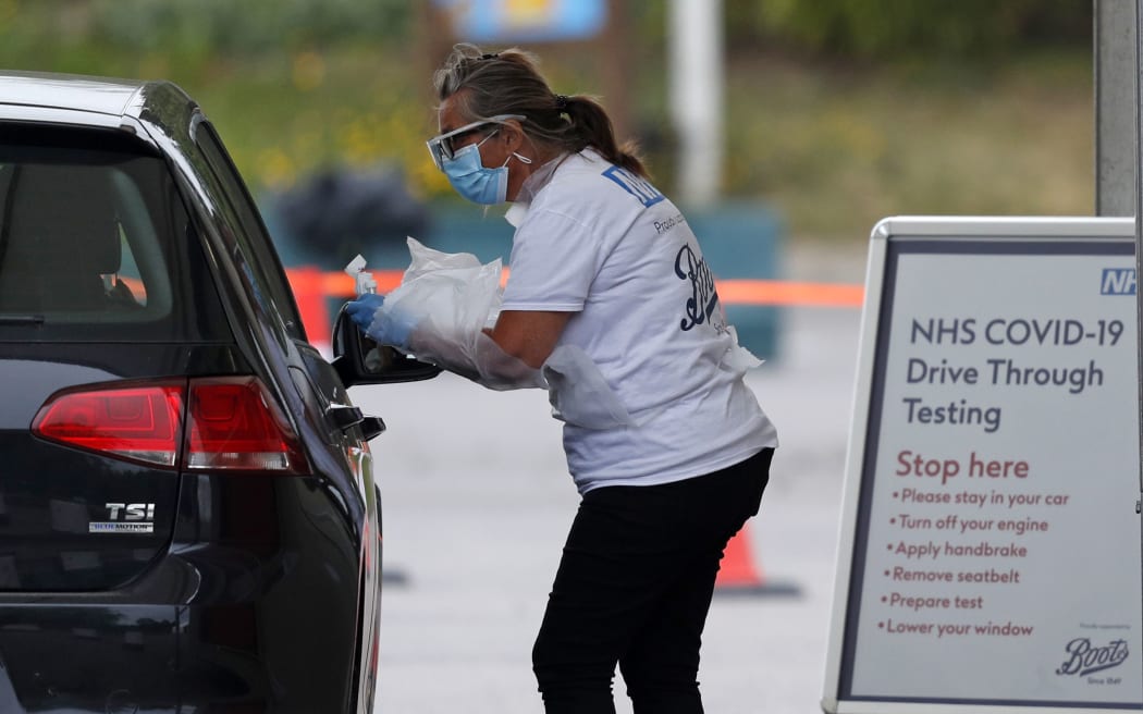 A medical worker tests a key worker for Covid-19 at a drive-in testing centre in the car park of Chessington World of Adventures, south of London, 10 May 2020.