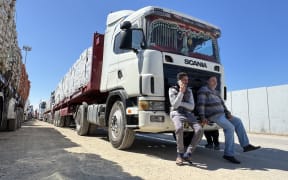 Image depicts trucks carrying humanitarian aid lining up on the Egyptian side of the Rafah border crossing with the Gaza Strip on March 2, 2025, after Israel suspended the entry of supplies into the Palestinian enclave.