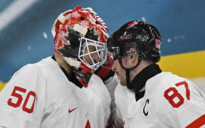 Canada's #87 Sidney Crosby (R) and Canada's #50 Jordan Binnington (L) celebrate at the 2026 Winter OLympics.