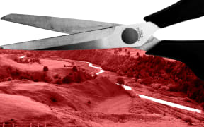 Scissors cutting through red colour image of hills and river