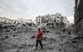 A Palestinian  man walks in front of the rubble of destroyed buildings and mosque after an Israeli air strikes in Gaza City, on October 9, 2023.