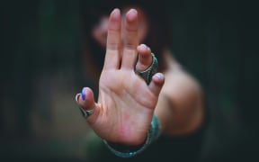 A woman holds her hand in the air in a blocking gesture.