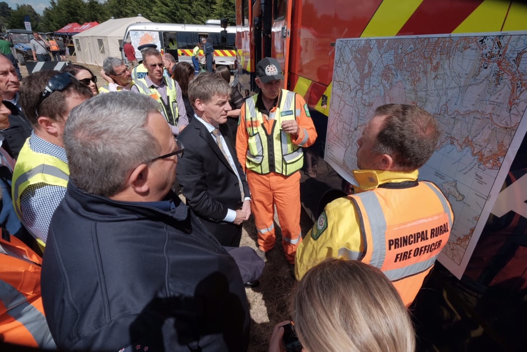 Prime Minister Bill English and Civil Defense Minister Gerry Brownlee are briefed by fire fighters