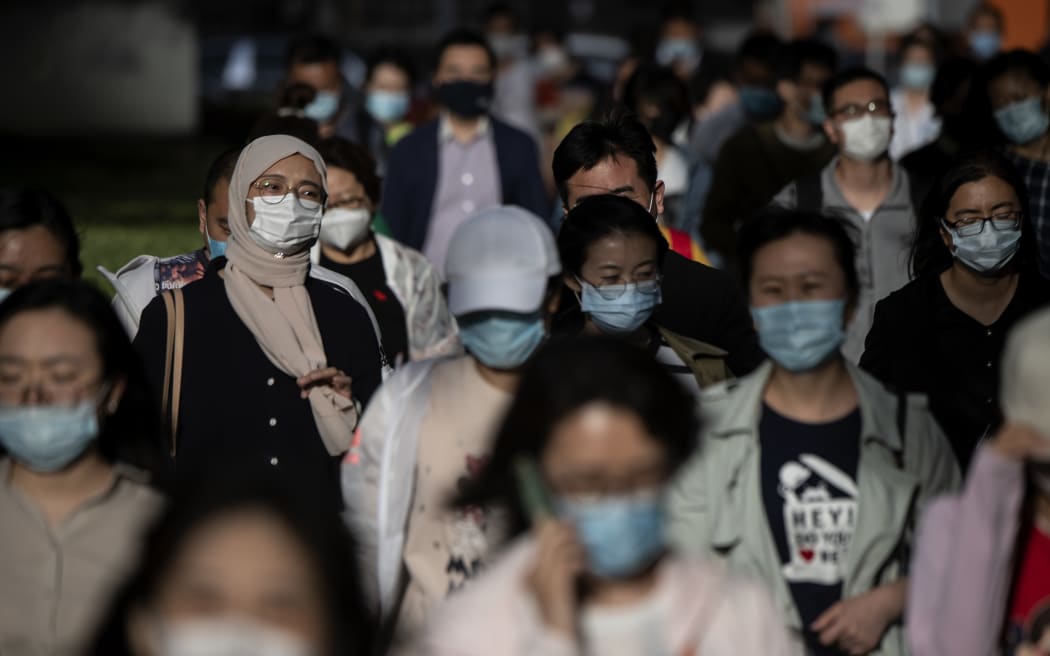 People wearing face masks walk to the subway during a rush hour in Beijing on May 12, 2020.
