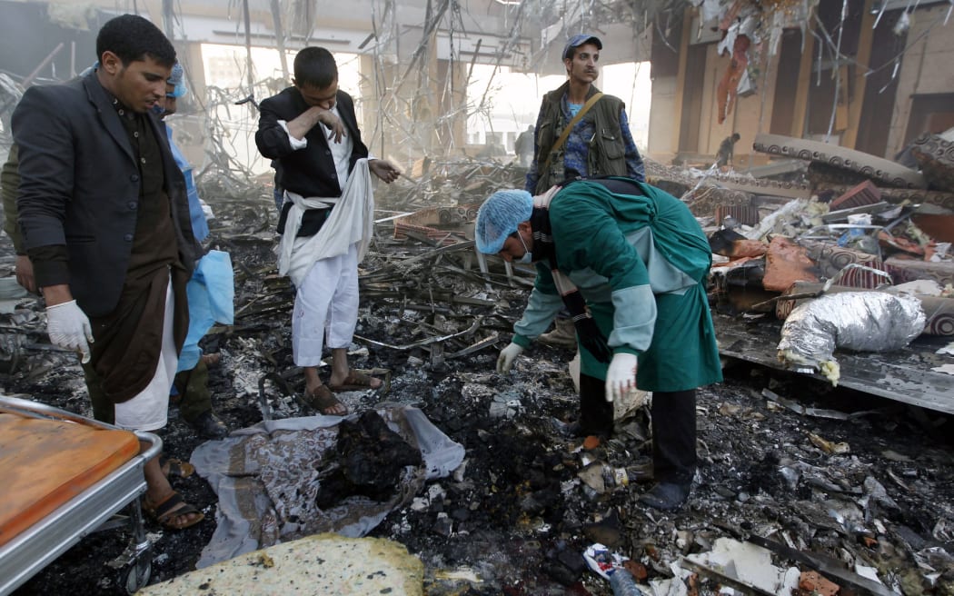 Yemeni rescue workers search for body parts amid the rubble of a destroyed building.