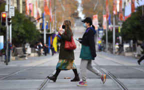 People wearing masks cross an almost empty shopping street in Melbourne on May 26, 2021, as Australia's second biggest city scrambles to contain a growing Covid-19 outbreak. (Photo by William WEST / AFP)
