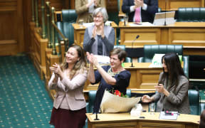 Green MPs Marama Davidson (left), Jan Logie (center) and Golriz Ghahraman  applaud Equal Employment Opportunities Commissioner Jackie Blue after the Domestic Violence Victims Protection Bill passes its third reading.