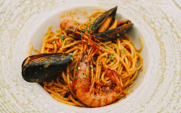 A plate of spaghetti with seafood and tomato sauce.