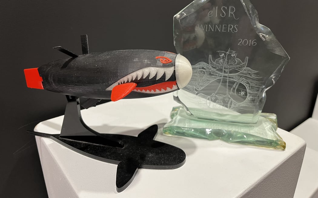 A small model of Taniwha, a human-powered submarine and the award it claimed in 2016.