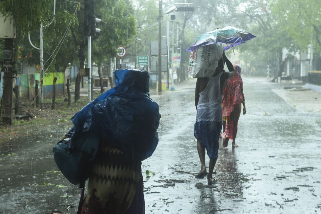 Residents walk along a street to a shelter ahead of the expected landfall of cyclone Amphan in Digha, West Bengal, on 20 May 2020.