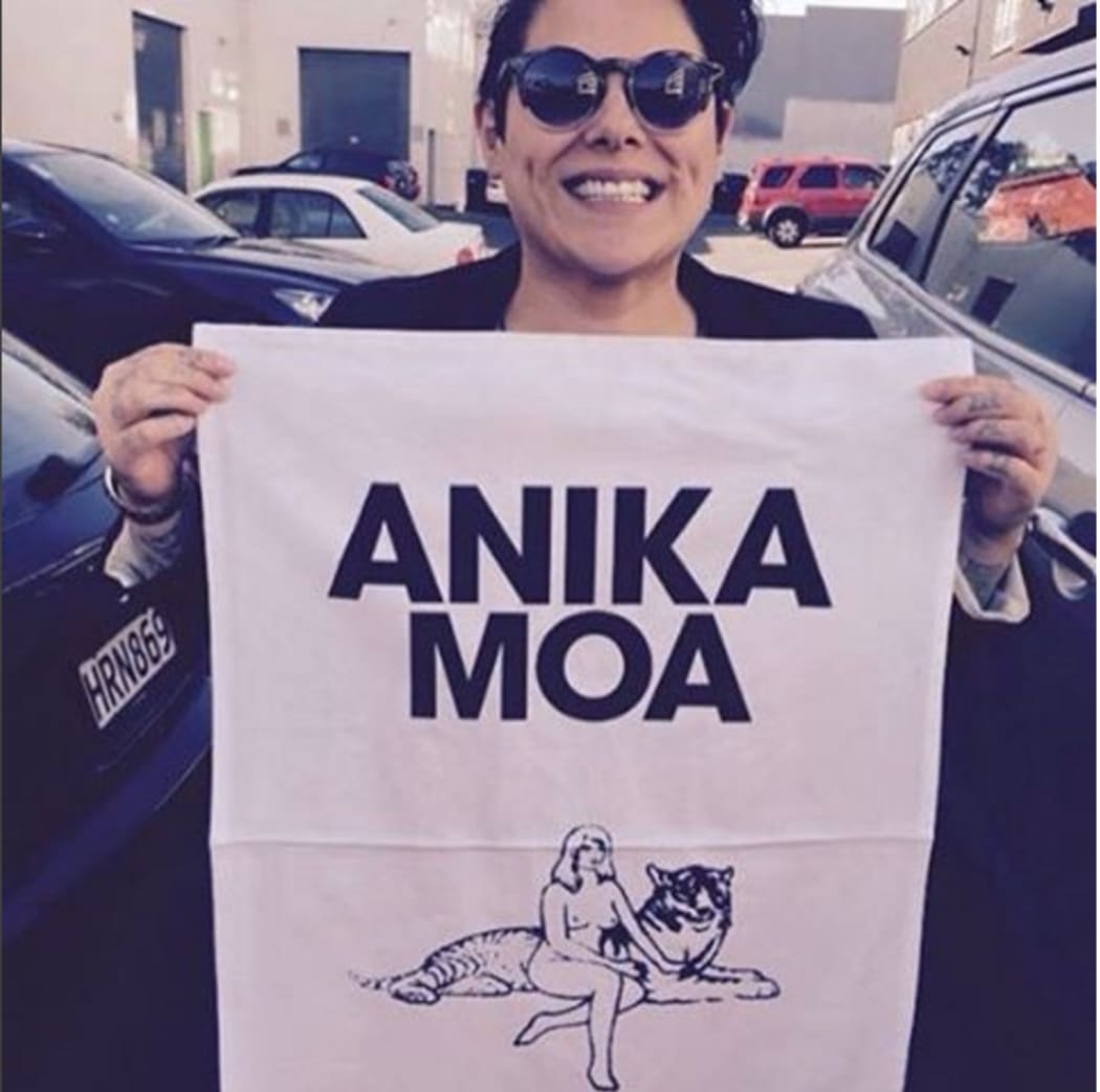 Anika Moa holding an Anika Moa-branded tea towel