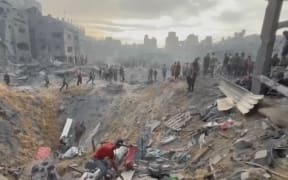 This image grab taken from AFPTV video footage shows Palestinians looking for survivors in a crater following a strike on a refugee camp in Jabalia on the northern Gaza Strip, on 31 October, 2023, amid relentless Israeli bombardment of the Palestinian territory.