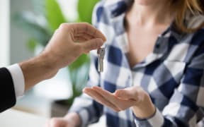 Young woman getting keys to new apartment from realtor. Family buys, rents new house. Customers or renters buy or rent real estate, close up