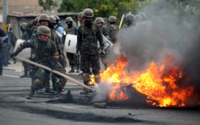 Riot police and soldiers try to remove burnt tires after clashes with supporters of the Honduran Opposition Alliance Against the Dictatorship in Tegucigalpa on Saturday.