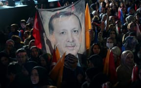 Supporters of Turkish President Tayyip Erdogan hold a flag of his portrait outside the AK Party headquarters in Ankara, Turkey, 15 May, 2023.
