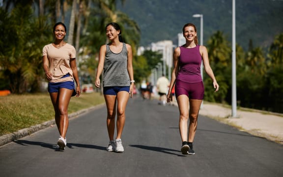 Three women taking a walk outdoors in exercise gear.