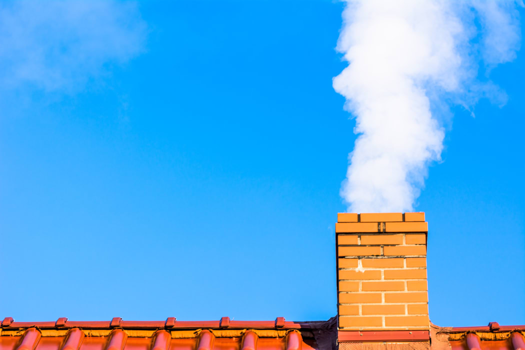 Modern house roof with chimney smoke, air pollution and smog in winter, ecological problems