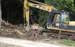 A digger helps clear forestry debris in Marahau after slips and flash flooding from Cyclone Gita.