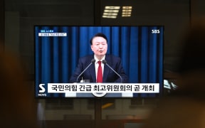 A television screen shows South Korea's President Yoon Suk Yeol speaking during a news broadcast at a train station in Seoul on December 3, 2024, after he declared emergency martial law, saying the step was necessary to protect the country from "communist forces" amid parliamentary wrangling over a budget bill. - "To safeguard a liberal South Korea from the threats posed by North Korea's communist forces and to eliminate anti-state elements... I hereby declare emergency martial law," Yoon said in a live televised address to the nation. (Photo by Anthony WALLACE / AFP)