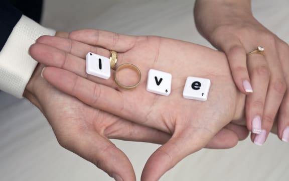A hand with scrabble letters and an engagement ring spelling love.