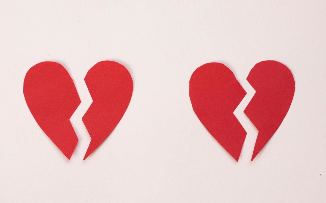 An image of two broken red hearts on a pale pink background