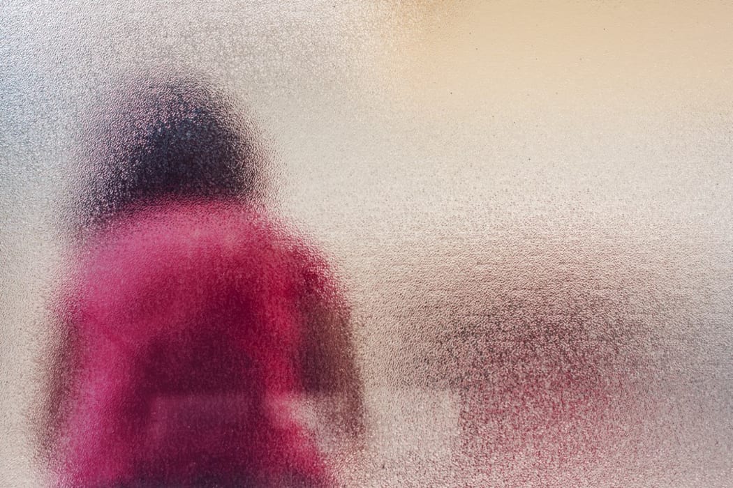 Silhouette of sad girl behind frosted glass. (Photo by IGOR STEVANOVIC / SCIENCE PHOTO / IST / Science Photo Library via AFP)