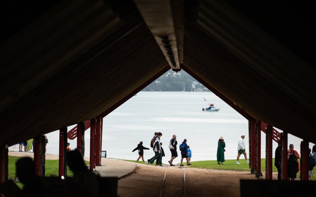 People heading past the boat shed down to the Lower Treaty Grounds, where the Waitangi Forum Tent is located, after the Waitangi Day dawn service.