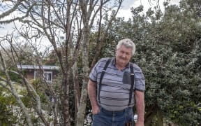 Riverside Drive resident Don Meads and dog Banjo near the kōwhai tree planted on the stopbank behind his house.