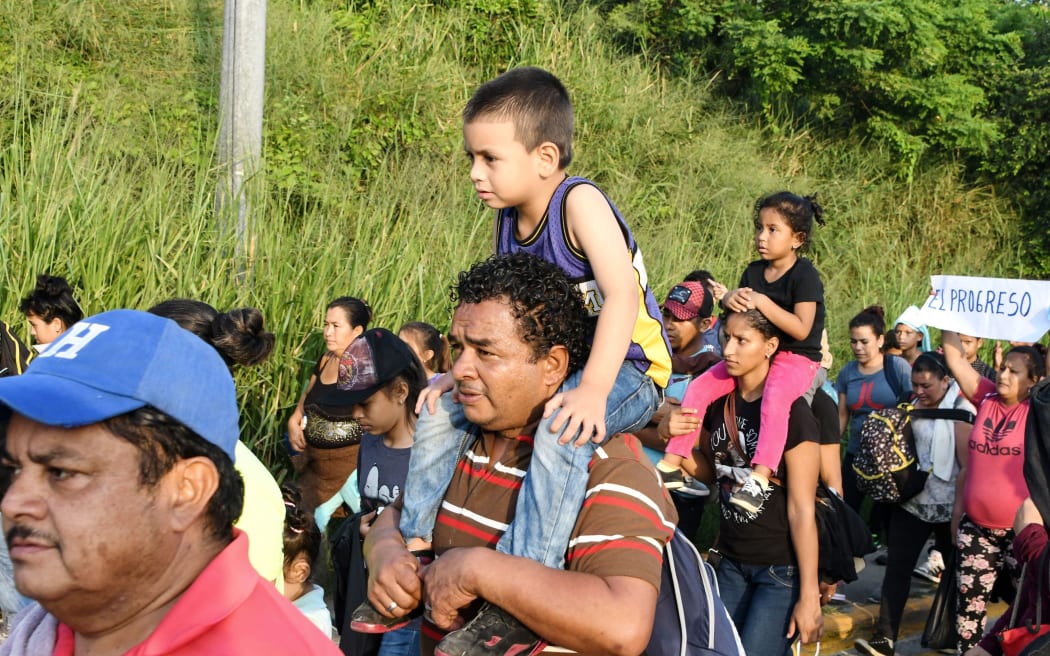 An Honduran man carries a child on is shoulders during an exodus towards the US from San Pedro Sula