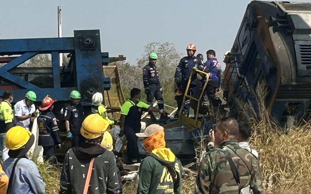 This UGC handout photo courtesy of Facebook user Smith Mikle taken and released on January 14, 2026 shows rescue workers next to the wreckage of a train crash after a construction crane collapse in Thailand's Nakhon Ratchasima province. A crane at an under-construction high-speed rail line in Thailand collapsed onto a passenger train on January 14, causing it to derail and killing at least 22 people, local authorities said. (Photo by Handout / Courtesy of Facebook user Smith Mikle / AFP) / NO USE AFTER JANUARY 24, 2026 05:20:07 GMT - NO USE AFTER JANUARY 24, 2026 05:20:07 GMT - RESTRICTED TO EDITORIAL USE – MANDATORY CREDIT «  AFP PHOTO / COURTESY OF FACEBOOK USER SMITH MIKLE » - NO MARKETING NO ADVERTISING CAMPAIGNS – DISTRIBUTED AS A SERVICE TO CLIENTS - NO ARCHIVE /