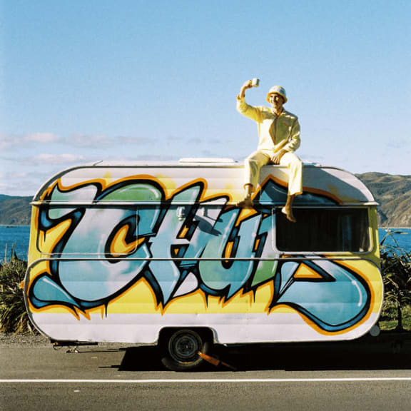 Cover image of the Casual Healing album, Driftwood. Artist sits on top of a caravan taking a selfie.