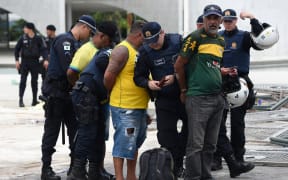 Security forces arrest supporters of Brazilian former President Jair Bolsonaro after retaking control of Planalto Presidential Palace in Brasilia on January 8, 2023. - Hundreds of supporters of Brazil's far-right ex-president Jair Bolsonaro broke through police barricades and stormed into Congress, the presidential palace and the Supreme Court Sunday, in a dramatic protest against President Luiz Inacio Lula da Silva's inauguration last week. (Photo by Ton MOLINA / AFP)