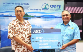 China's ambassador to Samoa Fei Mingxing hands over a ceremonial cheque for USD$200,000 to SPREP director of legal services anmd governing bodies Aumua Clark Peteru. Apia, Samoa 14 January 2025