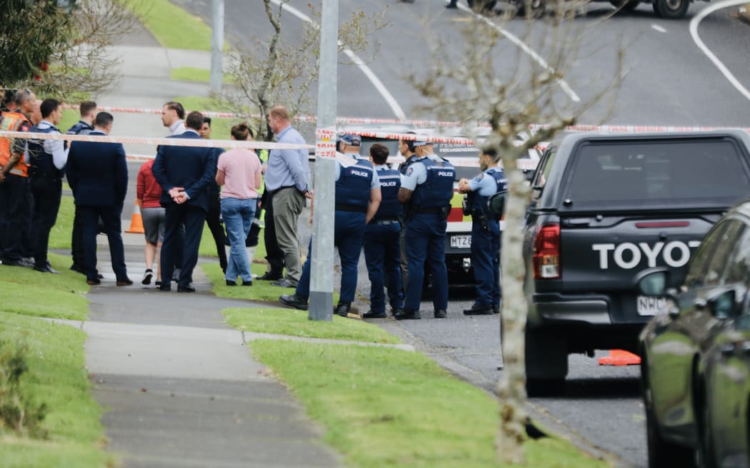 People speak to police inside the cordon on Murvale Drive.