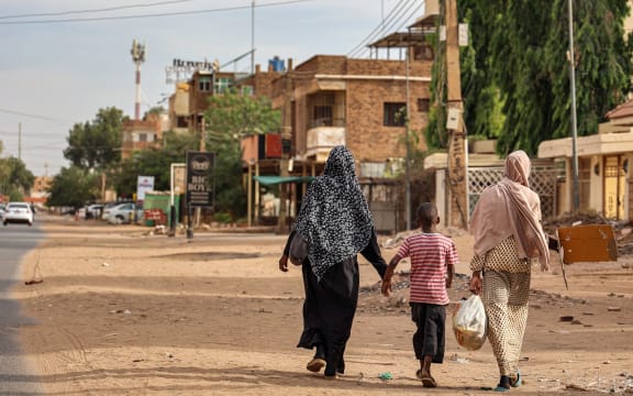 Women and a boy walk along a street in Khartoum on April 18, 2023. - Explosions rocked the Sudanese capital Khartoum on April 18, the fourth day of fighting that has claimed nearly 200 lives despite growing international calls for an end to hostilities that have spawned increasing lawlessness. (Photo by AFP)