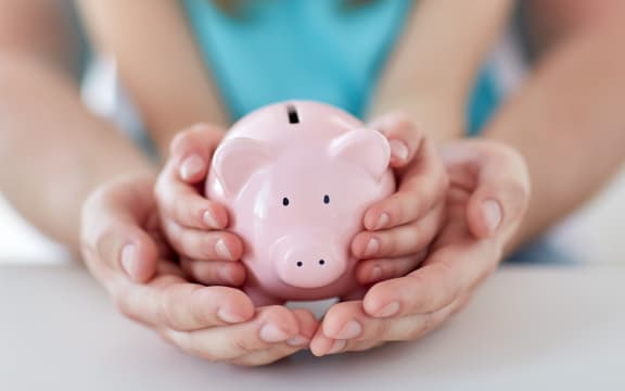 A man and a child hold a piggy bank