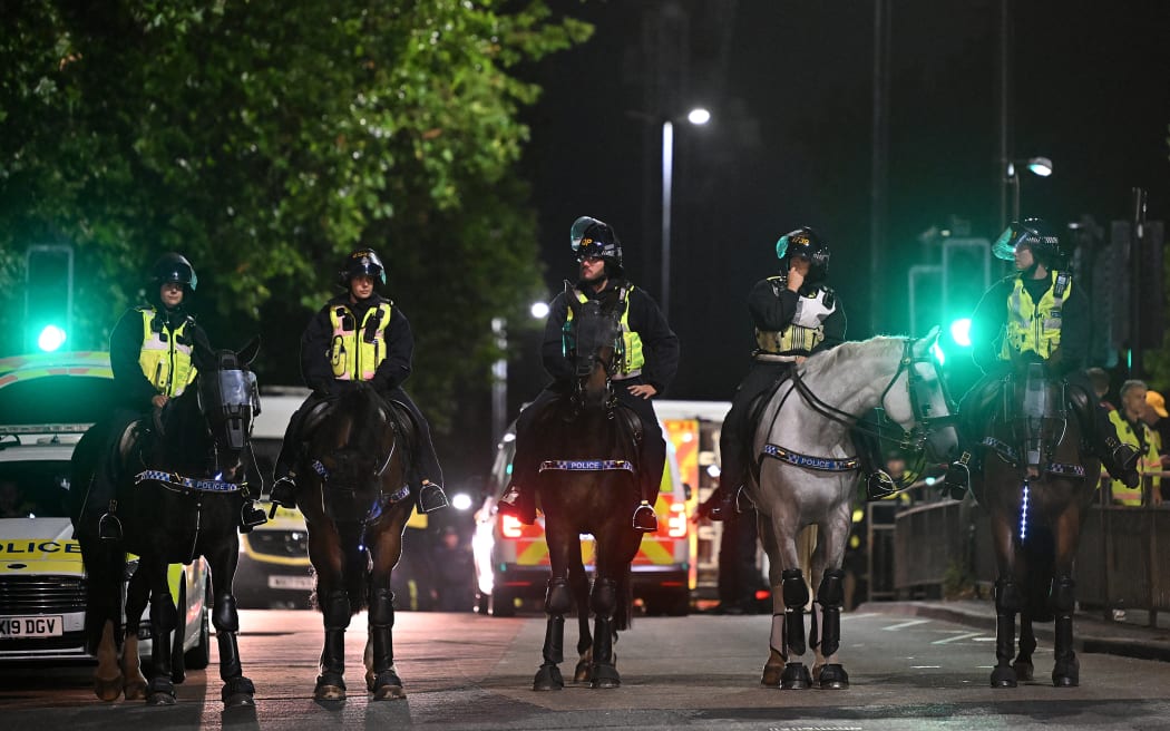 Mounted riot police stand guard outside a hotel housing asylum seekers to protect the premises from the 'Enough is Enough' demonstration called by far-right activists in Bristol on 3 August, 2024. Far-right protesters clashed with British police during tense rallies as unrest linked to disinformation about a mass stabbing that killed three young girls spread across the UK.