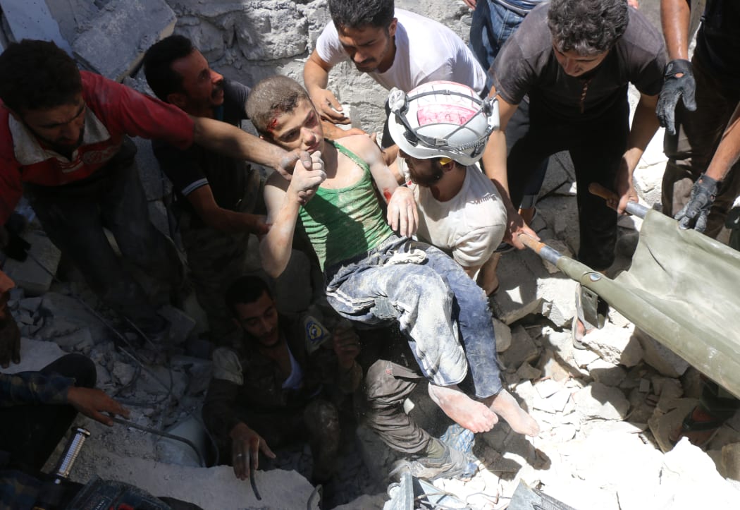 White Helmet volunteers carry a boy they rescued from rubble in Aleppo.