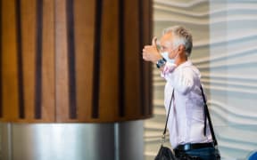 A passenger gives a thumbs-up as he walks into the arrivals hall after flying from Sydney to Auckland Airport.